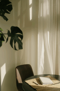 Sunlight filters across a quiet table with a closed notebook and pen, evoking calm, clarity, and the ease of systems that support your business behind the scenes.