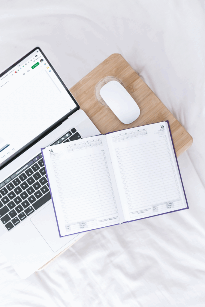 Laptop and open planner on a soft surface, representing relaxed but focused business planning.